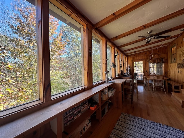 sunroom featuring wood walls, vaulted ceiling with beams, and wood finished floors