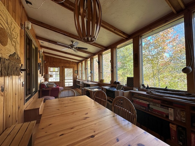 sunroom / solarium featuring vaulted ceiling with beams, wooden walls, outdoor dining area, and a ceiling fan