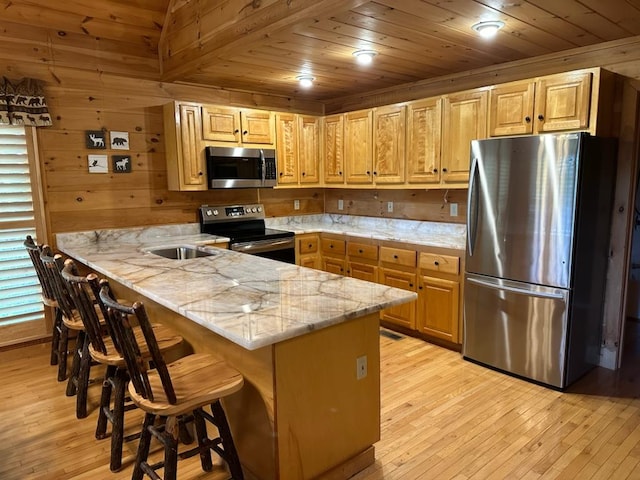 kitchen featuring wood ceiling, stainless steel appliances, kitchen peninsula, and a breakfast bar area