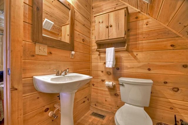 bathroom with toilet and wood walls