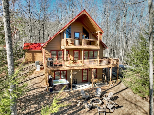 back of property featuring a patio area, a balcony, a hot tub, a deck, and a fire pit