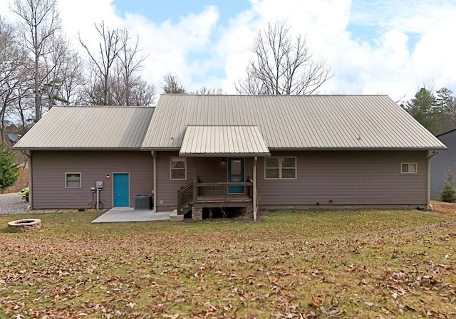 rear view of property featuring a patio area, an outdoor fire pit, metal roof, and a lawn