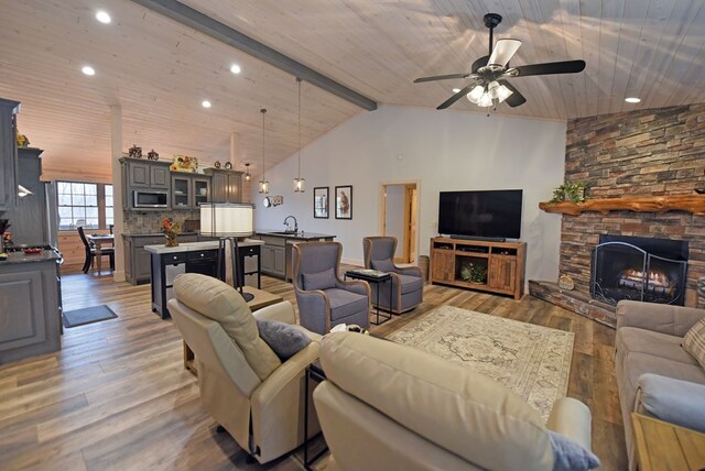 living area with beam ceiling, a stone fireplace, wood finished floors, high vaulted ceiling, and wooden ceiling