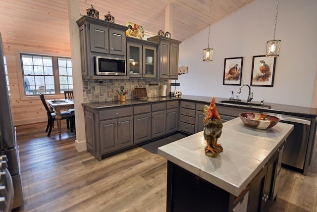 kitchen featuring lofted ceiling, appliances with stainless steel finishes, light wood-type flooring, and a sink