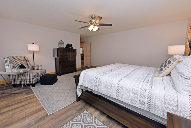 bedroom with ceiling fan, wood finished floors, and baseboards