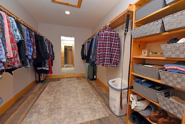 walk in closet with wood finished floors and attic access