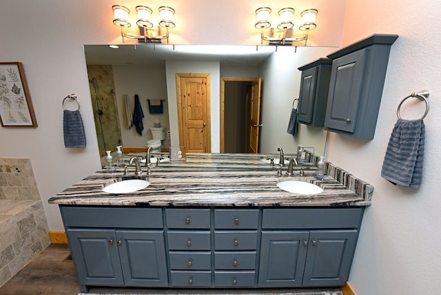 full bathroom featuring a shower, a sink, toilet, and double vanity