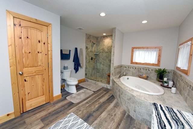 full bath featuring toilet, a stall shower, a tub with jets, and wood finished floors