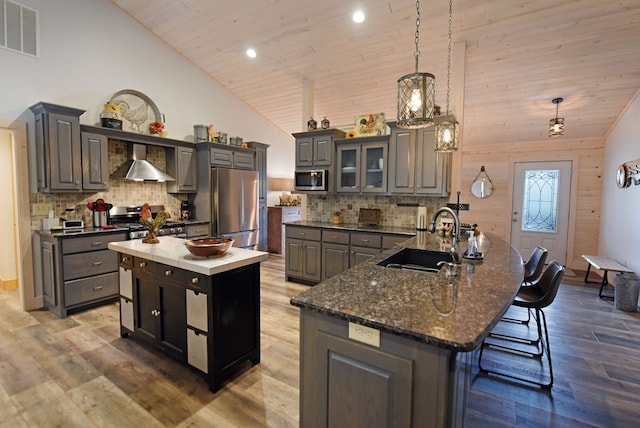 kitchen featuring visible vents, appliances with stainless steel finishes, a sink, wall chimney range hood, and high vaulted ceiling