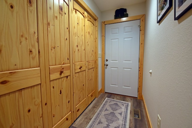 doorway with visible vents, wood finished floors, and a textured wall