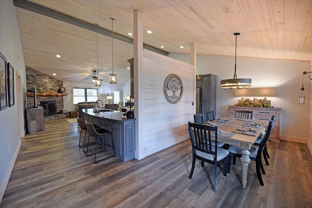 dining space with vaulted ceiling, a stone fireplace, dark wood-type flooring, and wooden ceiling