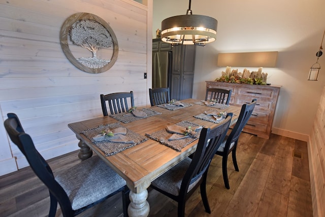 dining space with hardwood / wood-style flooring, baseboards, and a chandelier