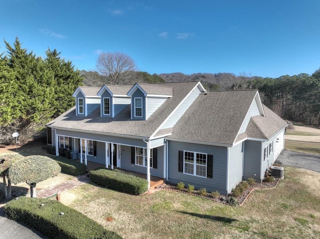 new england style home with a porch, a front yard, and cooling unit