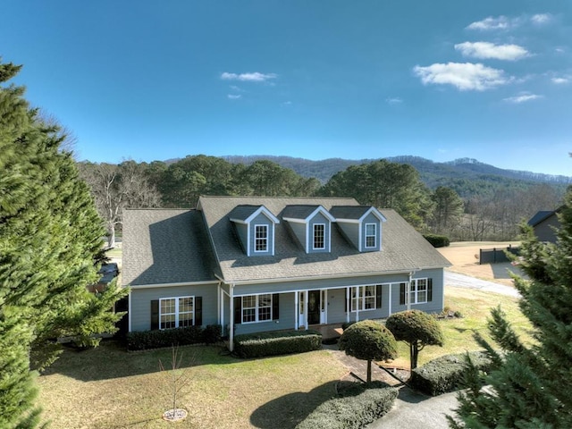 cape cod house featuring a mountain view, a porch, and a front yard