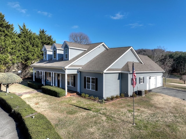 new england style home featuring a porch, a garage, central air condition unit, and a front lawn