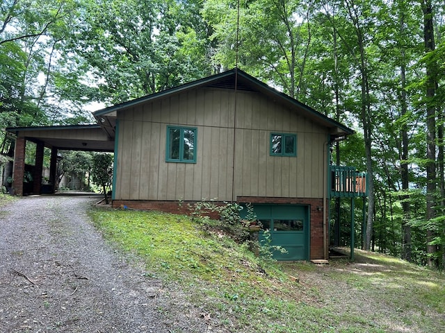 view of side of home featuring brick siding, an attached carport, driveway, and a garage