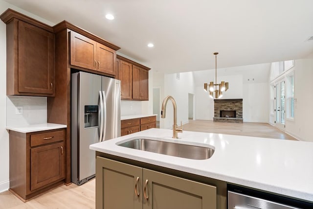 kitchen featuring light wood-type flooring, pendant lighting, sink, and stainless steel fridge with ice dispenser