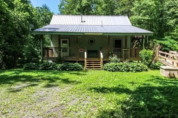 back of house featuring a lawn and covered porch