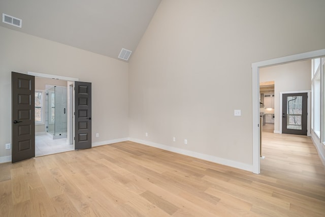 unfurnished bedroom with visible vents, light wood finished floors, and high vaulted ceiling
