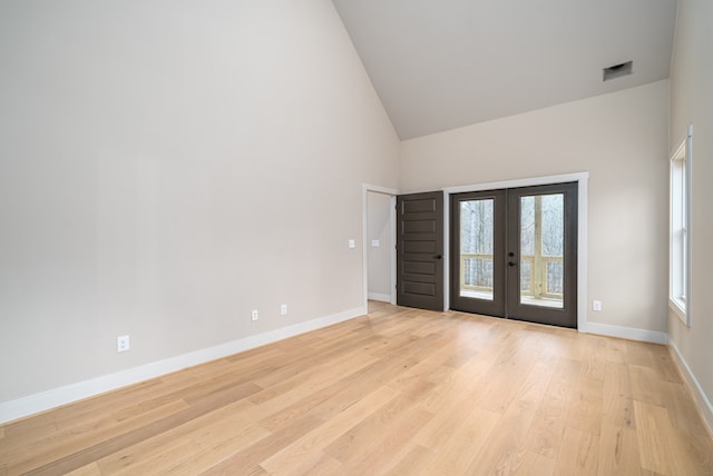 empty room featuring visible vents, baseboards, high vaulted ceiling, light wood-type flooring, and french doors