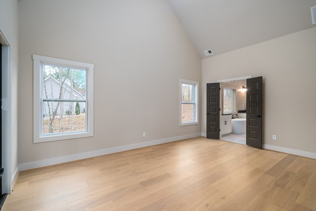 unfurnished bedroom with baseboards, high vaulted ceiling, visible vents, and light wood-style flooring