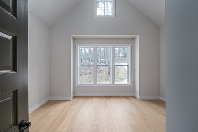 interior space with a healthy amount of sunlight, baseboards, light wood-style flooring, and lofted ceiling