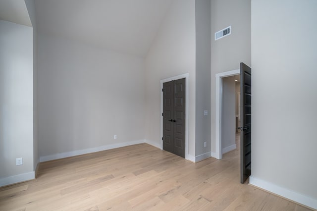 unfurnished bedroom featuring high vaulted ceiling, baseboards, light wood finished floors, and visible vents