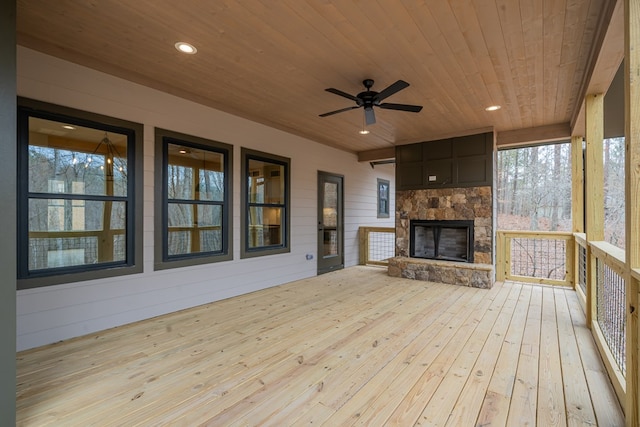 wooden deck with an outdoor stone fireplace and ceiling fan