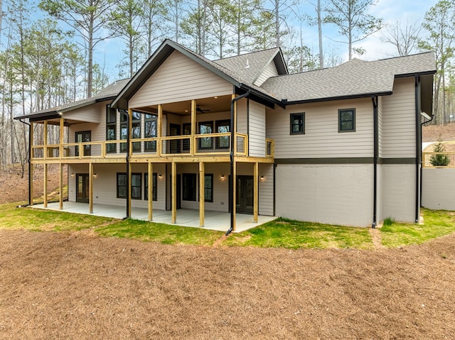 rear view of house featuring roof with shingles, a ceiling fan, a patio area, and a wooden deck