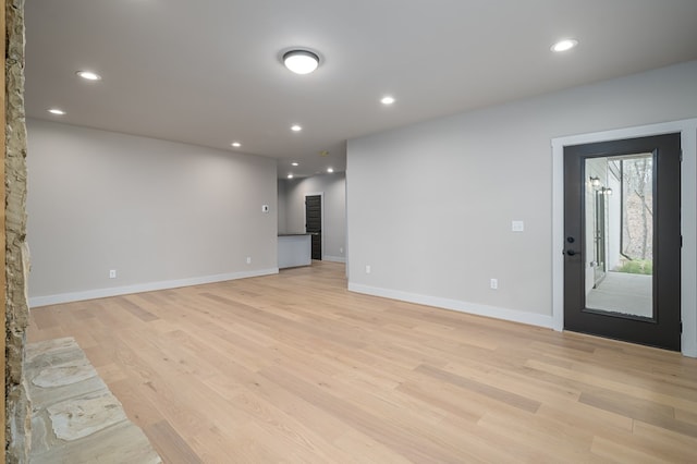 unfurnished living room with recessed lighting, baseboards, and light wood finished floors
