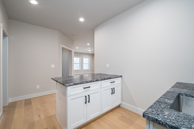 kitchen with light wood-style floors, baseboards, white cabinets, and a peninsula