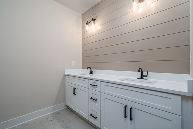 full bath with wooden walls, baseboards, a sink, and marble finish floor