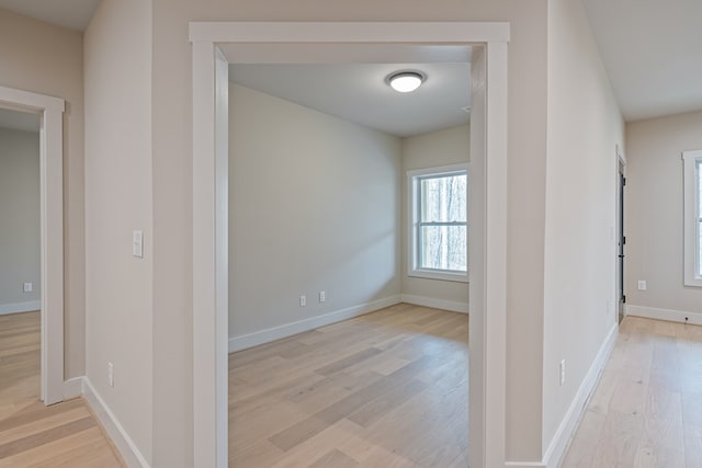corridor featuring baseboards and wood finished floors