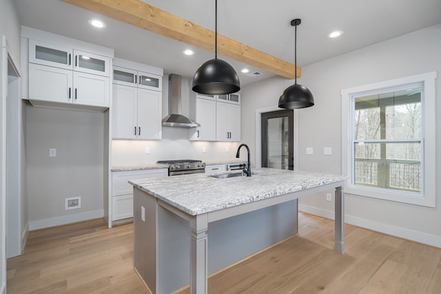 kitchen featuring wall chimney range hood, recessed lighting, a sink, and stainless steel gas range