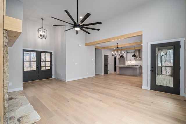 foyer with french doors, light wood-style floors, plenty of natural light, and high vaulted ceiling