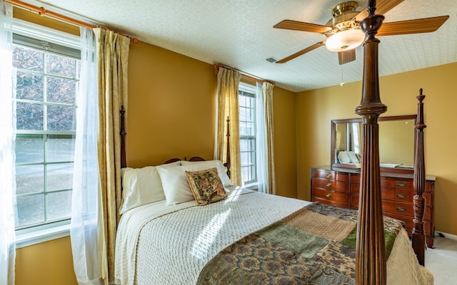 bedroom with a textured ceiling, carpet floors, and ceiling fan