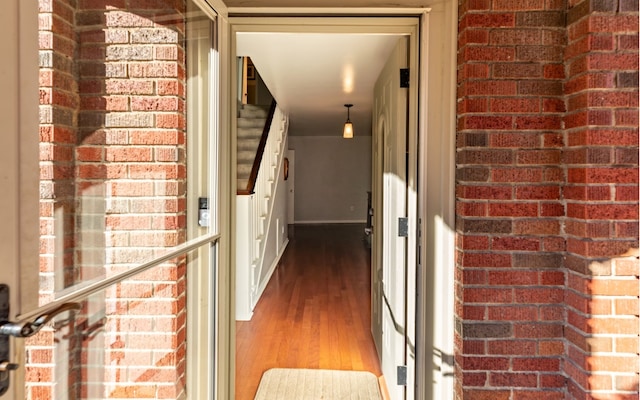 interior space with brick wall and hardwood / wood-style floors