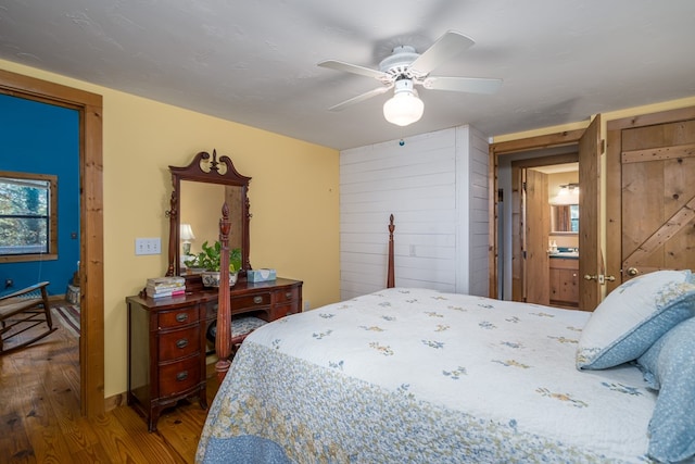 bedroom with connected bathroom, hardwood / wood-style floors, and ceiling fan