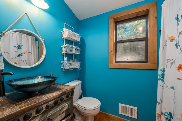 bathroom with vanity, lofted ceiling, wood-type flooring, and toilet