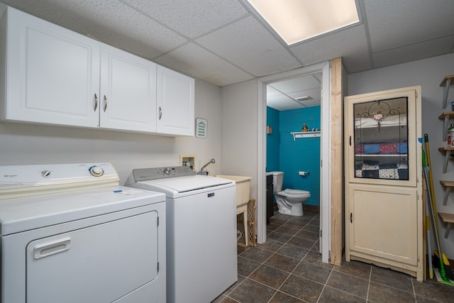 laundry room with cabinets, sink, washing machine and clothes dryer, and dark tile patterned flooring