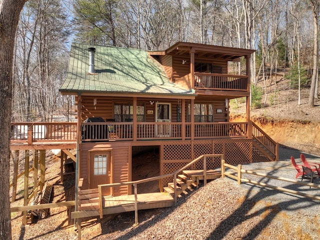 back of property with metal roof, a deck, and stairs