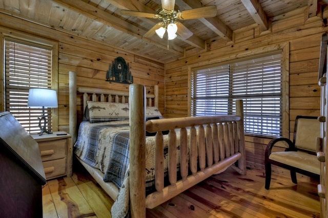 bedroom featuring beam ceiling, wood walls, wood ceiling, and light wood-type flooring