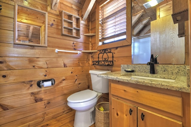 half bath featuring vanity, wooden walls, and toilet