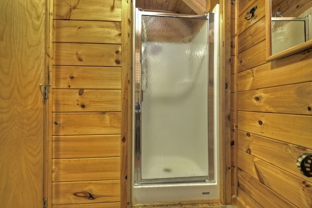 bathroom featuring a stall shower and wood walls