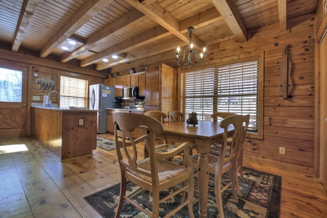 dining area featuring a chandelier, wood walls, wooden ceiling, and light wood-style flooring