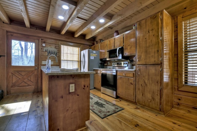 kitchen with light wood-type flooring, plenty of natural light, appliances with stainless steel finishes, and brown cabinetry