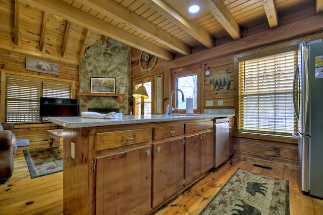 kitchen with a sink, stainless steel appliances, wooden walls, wooden ceiling, and vaulted ceiling with beams