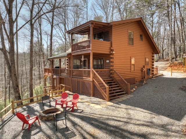 rear view of property with a fire pit, a wooden deck, a balcony, log exterior, and stairs