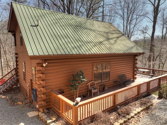 view of home's exterior with log siding and a deck