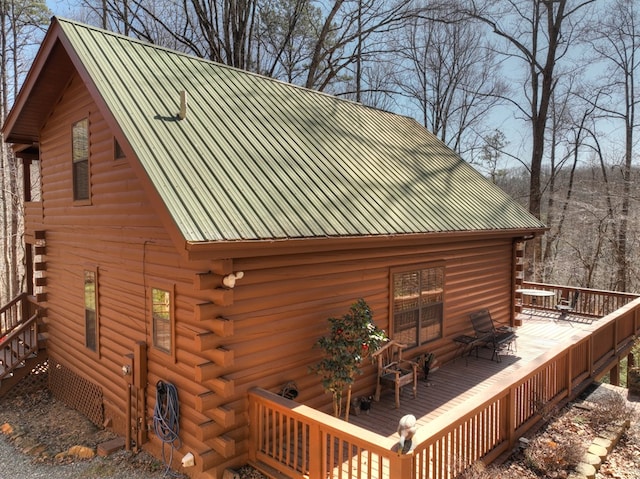 view of side of home featuring log siding, metal roof, and a deck